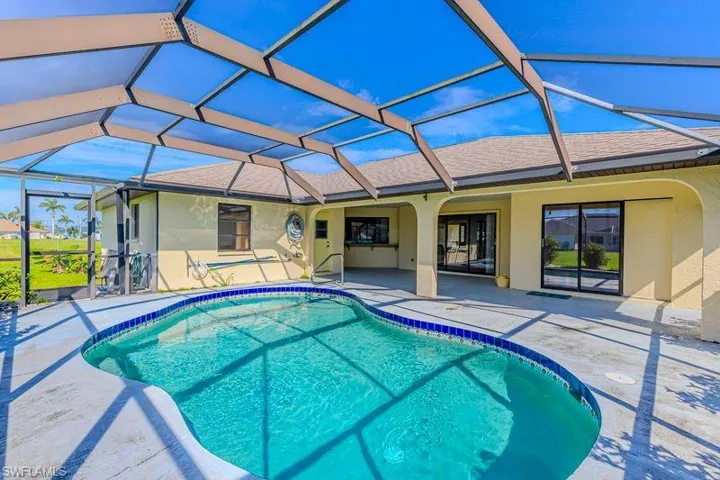 Outdoor pool featuring a sunroom, a patio area, and glass enclosure