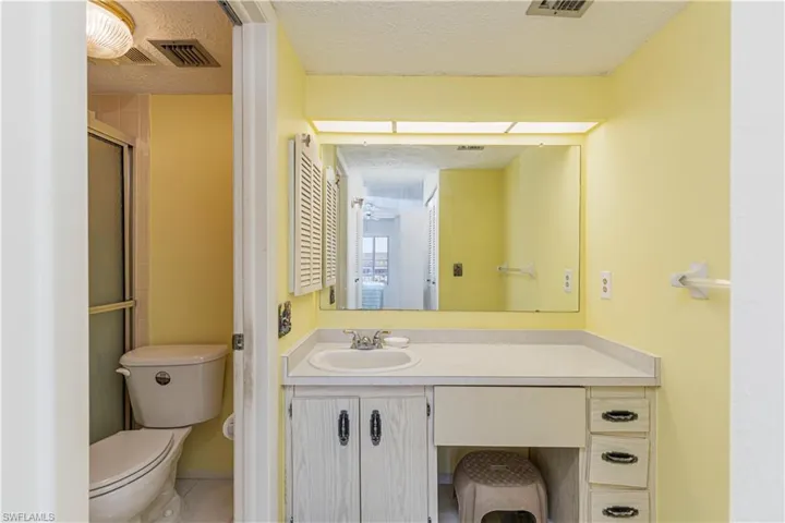 Full bath with vanity, a textured ceiling, an enclosed shower, and tile patterned floors