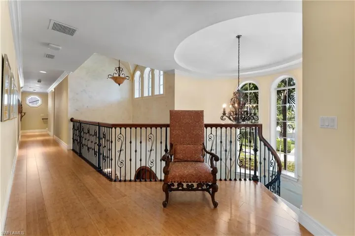 Living area with a healthy amount of sunlight, a notable chandelier, hardwood / wood-style flooring, and ornamental molding