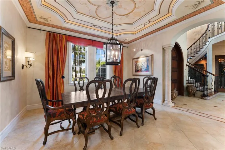Dining room featuring ornamental molding, a notable chandelier, a tray ceiling, and ornate columns