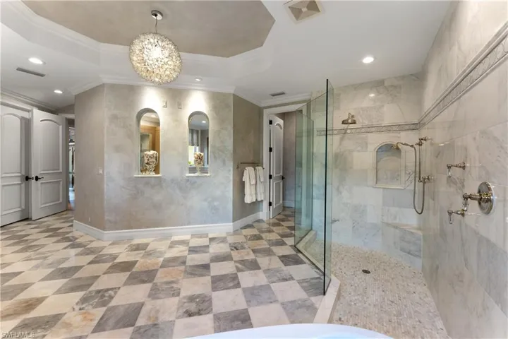 Bathroom with ornamental molding, walk in shower, a chandelier, and a tray ceiling