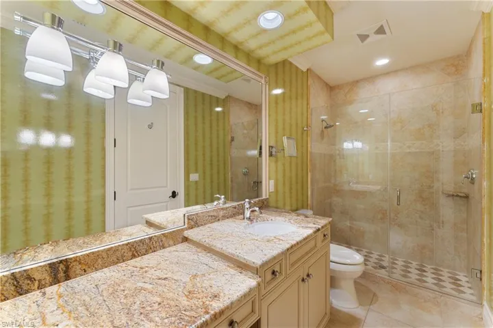 Bathroom with toilet, a shower with shower door, vanity, and tile patterned floors