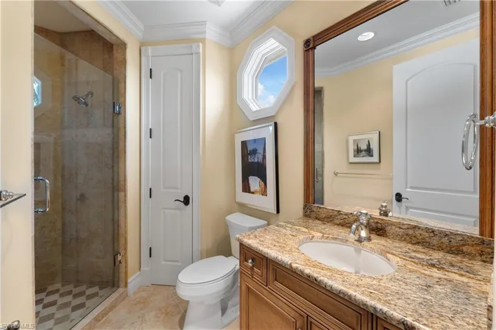Bathroom with vanity, crown molding, a shower with shower door, and toilet