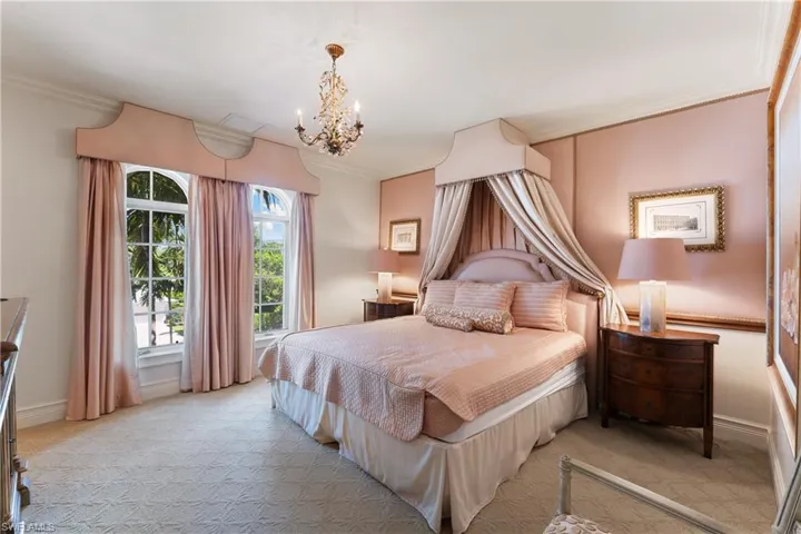 Bedroom with crown molding, light colored carpet, and a notable chandelier