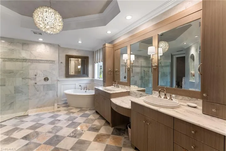 Bathroom with vanity, independent shower and bath, an inviting chandelier, and a raised ceiling