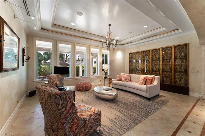 Living room with an inviting chandelier, ornamental molding, and a tray ceiling