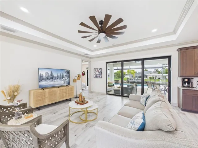 Expansive living area featuring large format tile flooring and a tray ceiling with recessed lighting