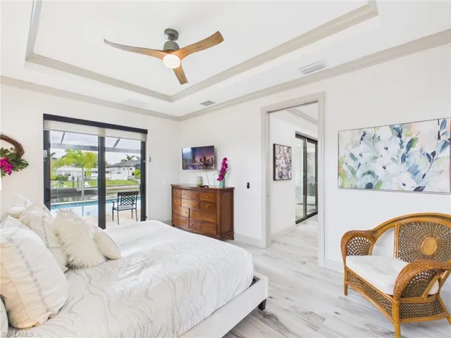 Tray ceiling with decorative molding and a modern ceiling fan, featuring sliding glass doors to outdoor spaces