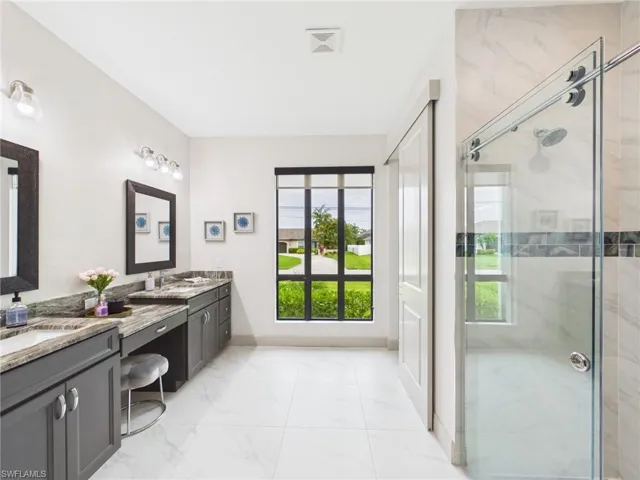 Spacious bathroom featuring a dual vanity with undermount sinks, stone countertops, and dark cabinetry