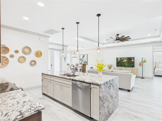 Kitchen island featuring a stainless steel dishwasher, undermount sink, and granite countertop