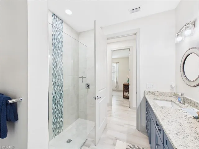 Bathroom featuring a glass-enclosed shower with decorative vertical tile inlay, shower bench, and recessed lighting