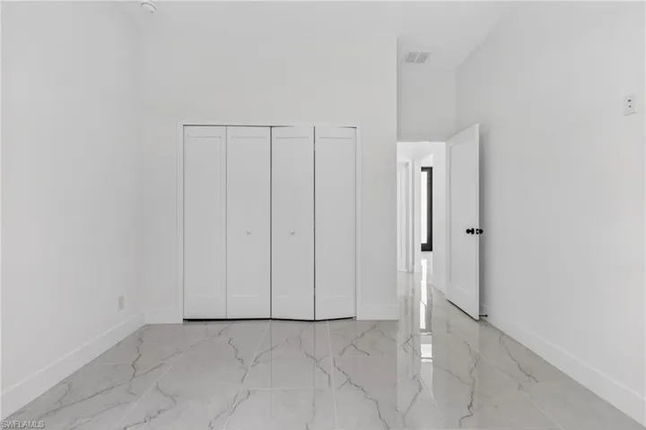 Unfurnished bedroom with a closet, a high ceiling, and light marble finish floors