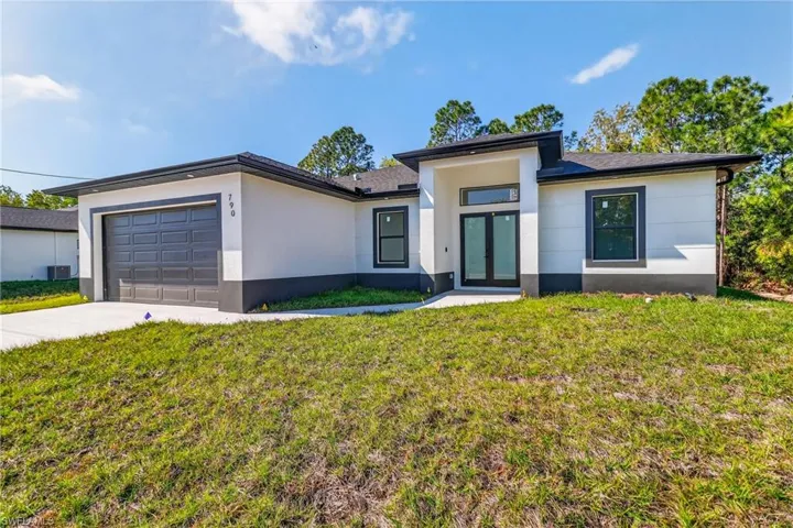 Prairie-style house featuring a front lawn, stucco siding, an attached garage, and driveway