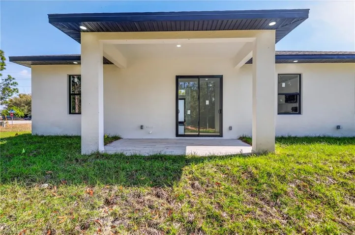Back of house with a patio, stucco siding, and a yard