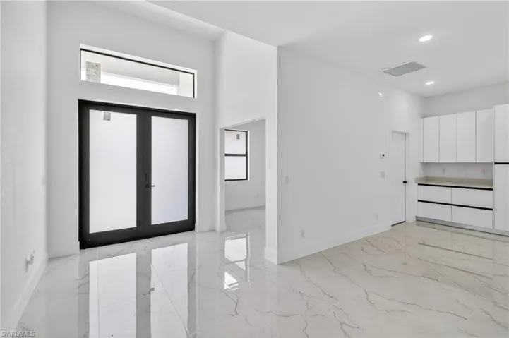 Entryway featuring french doors, light marble finish flooring, and recessed lighting