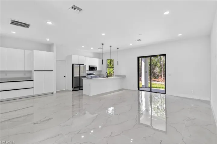 Kitchen featuring white cabinets, a peninsula, pendant lighting, and open floor plan
