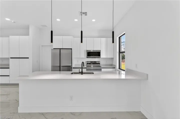 Kitchen with white cabinets, stainless steel appliances, a peninsula, and modern cabinets