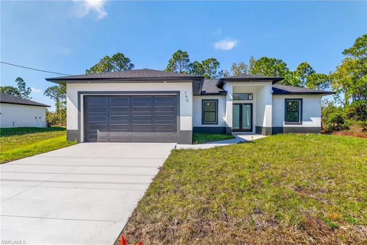 Prairie-style house with a front yard, stucco siding, concrete driveway, and a garage