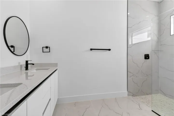 Full bathroom featuring a marble finish shower and double vanity