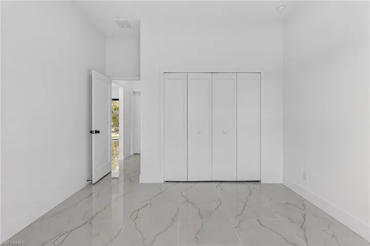 Unfurnished bedroom featuring a high ceiling, a closet, and light marble finish floors