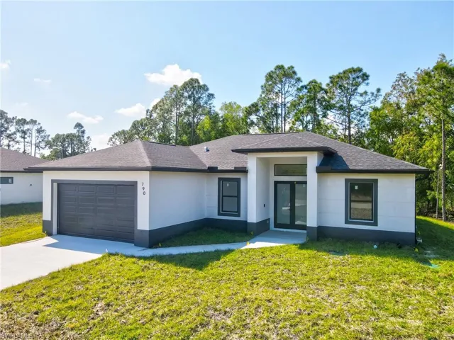 View of front of home with a front yard, a garage, and concrete driveway