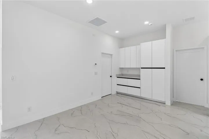 Unfurnished bedroom with light marble finish floors and recessed lighting