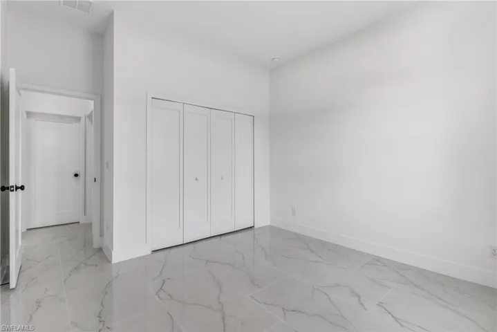 Unfurnished bedroom featuring a closet and light marble finish floors