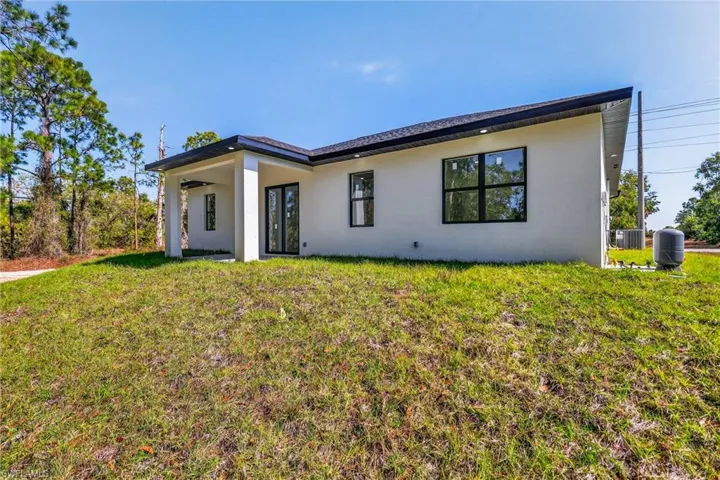 View of front of house with stucco siding, a front lawn, and a patio