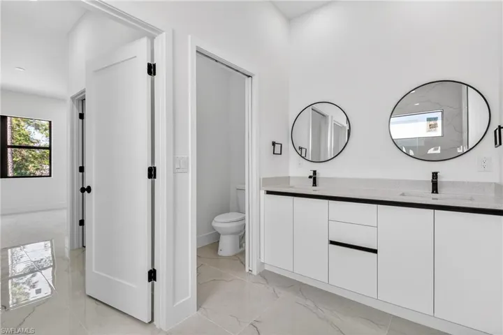 Full bathroom with healthy amount of natural light, light marble finish flooring, and double vanity