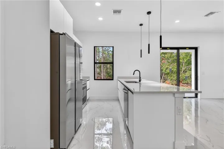 Kitchen featuring white cabinets, modern cabinets, stainless steel appliances, and healthy amount of natural light