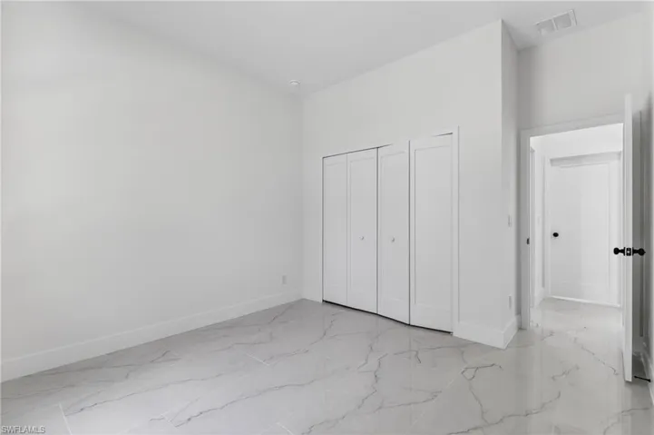 Unfurnished bedroom with light marble finish floors and a closet