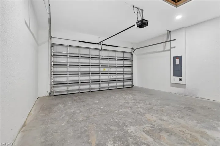 Garage with electric panel, a garage door opener, and a textured wall