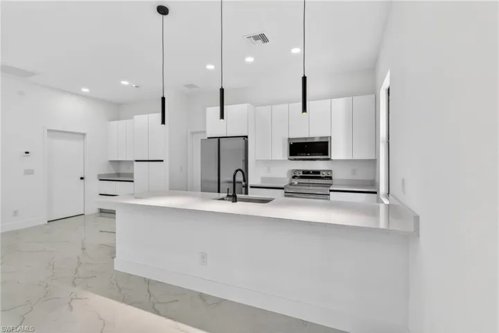 Kitchen with white cabinets, stainless steel appliances, light marble finish floors, and modern cabinets