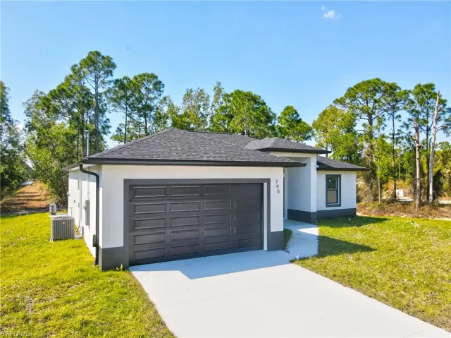 View of front of home featuring a front lawn, stucco siding, concrete driveway, roof with shingles, and an attached garage