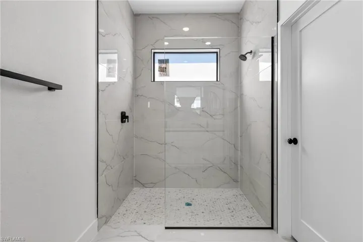 Full bath featuring a marble finish shower and baseboards