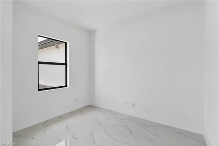 Spare room featuring light marble finish floors and baseboards