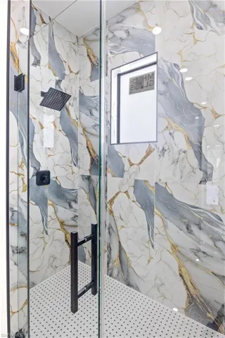 Full bath with a marble finish shower