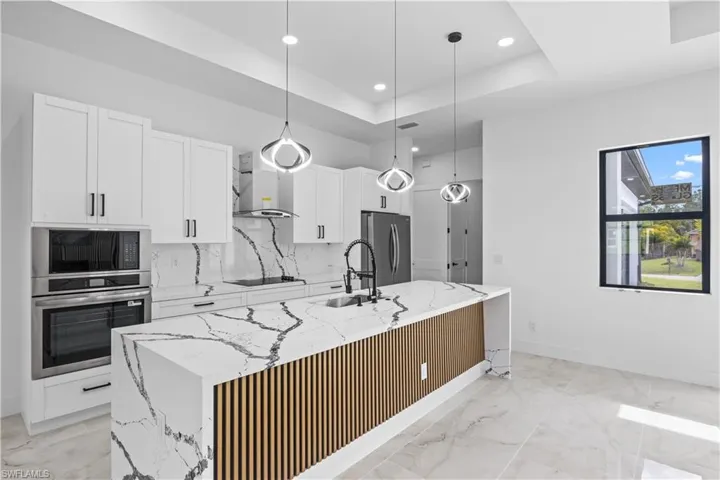 Kitchen with white cabinetry, light stone counters, stainless steel appliances, and recessed lighting
