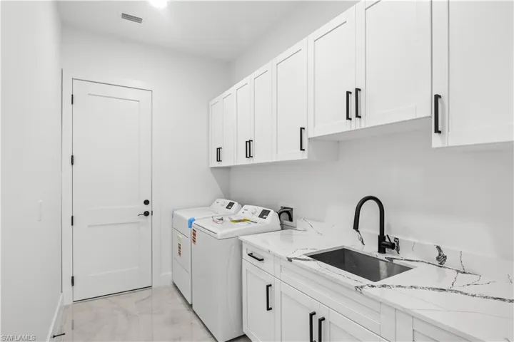 Laundry room with cabinet space, light marble finish flooring, and washing machine and clothes dryer