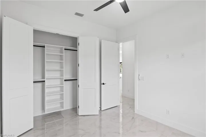 Unfurnished bedroom with light marble finish flooring, a closet, and ceiling fan