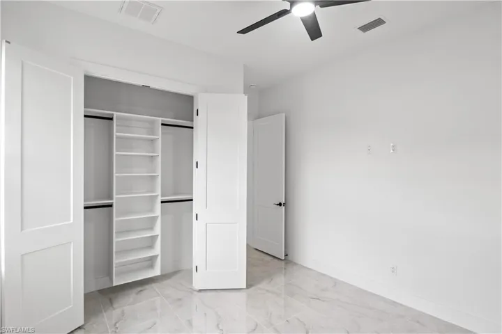 Unfurnished bedroom featuring light marble finish floors, a closet, and a ceiling fan