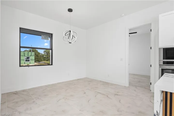 Unfurnished dining area featuring a chandelier and light marble finish floors
