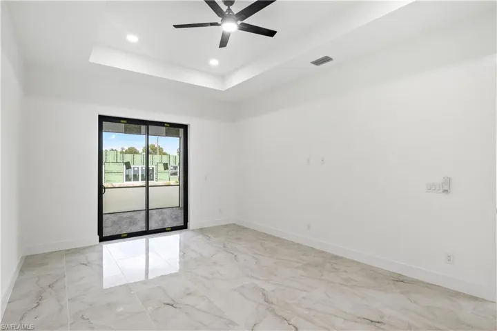 Spare room featuring light marble finish floors, a tray ceiling, a ceiling fan, and recessed lighting