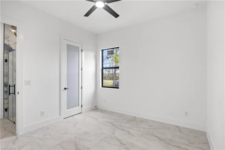 Unfurnished bedroom with a ceiling fan and light marble finish flooring
