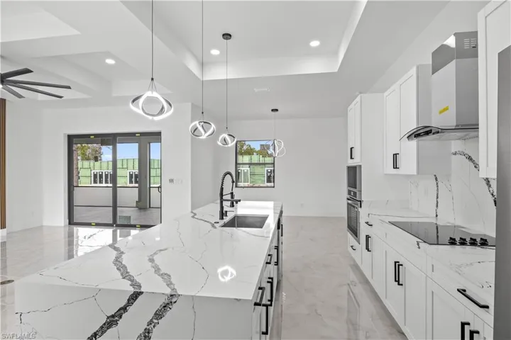 Kitchen featuring light stone countertops, healthy amount of natural light, decorative light fixtures, white cabinetry, and recessed lighting