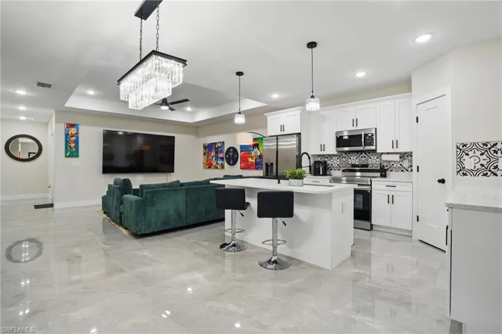 Kitchen featuring stainless steel appliances, light marble finish floors, backsplash, baseboards, and recessed lighting