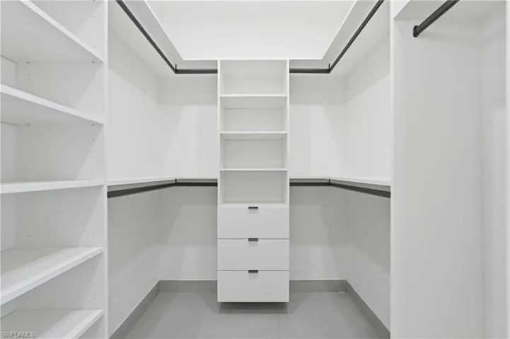 Custom closet system featuring extensive shelving, central drawer stack, and multiple hanging rods for optimized storage