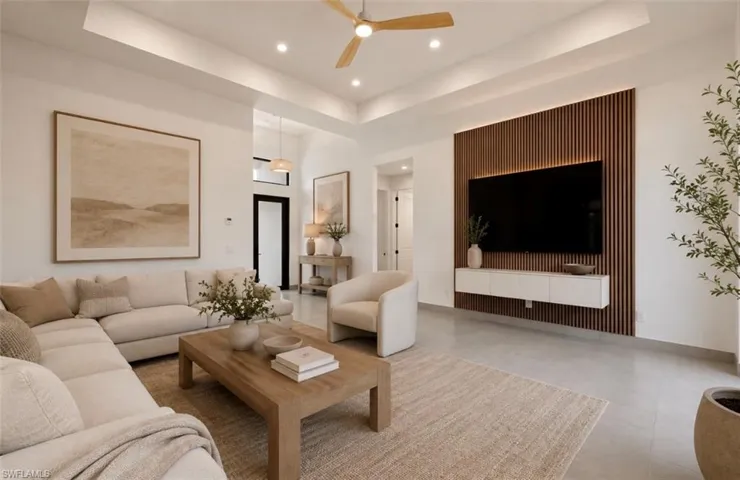 Spacious living area featuring a wood-slat accent wall with integrated backlighting, a ceiling fan, recessed lighting, a tray ceiling, and hard-surface flooring