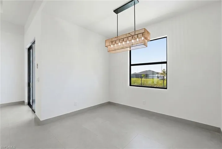 Spacious room featuring light gray tile flooring, a modern linear chandelier, and a large black-framed window