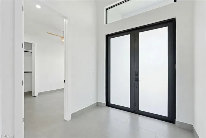 Contemporary double entry doors with frosted glass panels, transom window, and matte black hardware